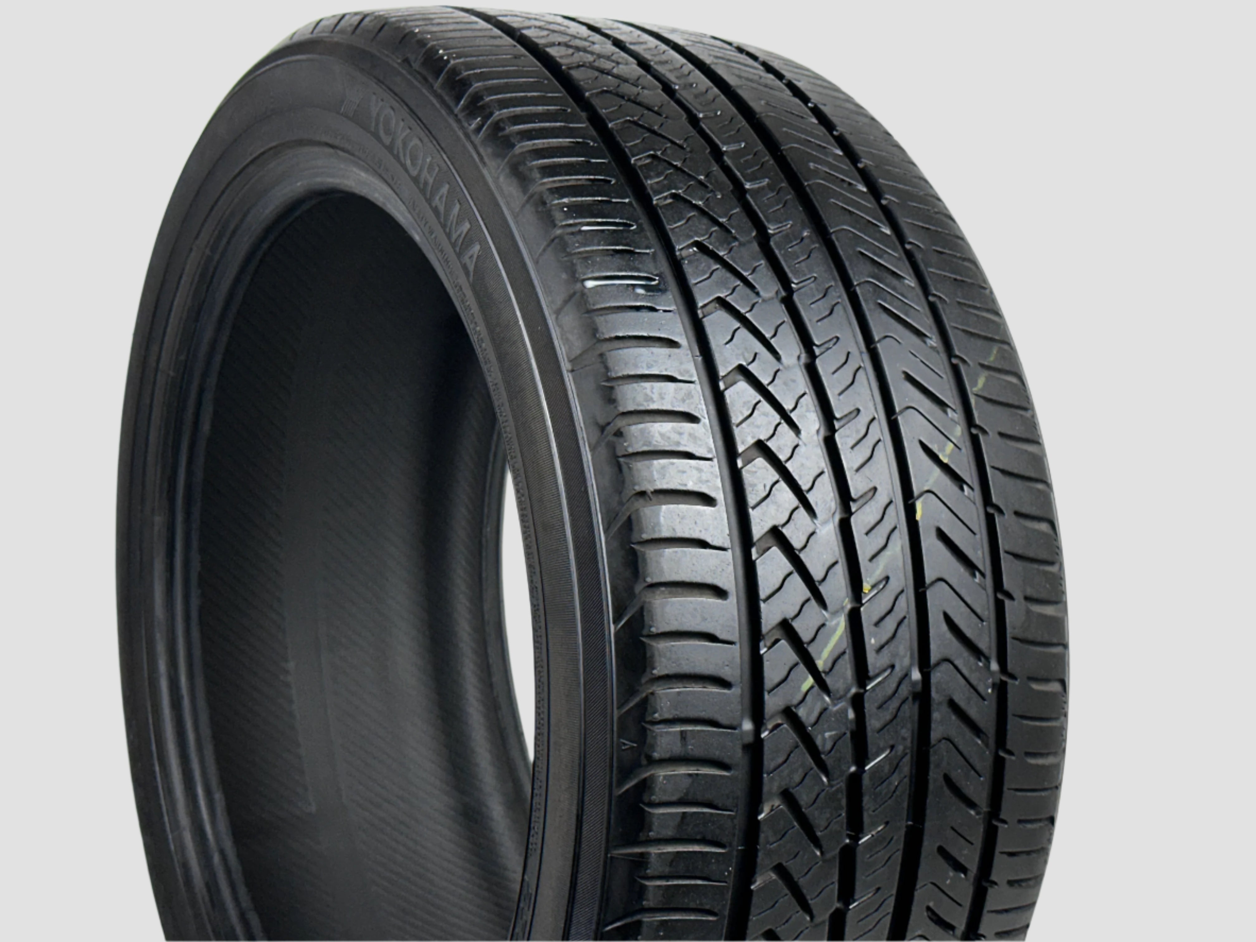 Close-up of a car tire with tread pattern on a white background